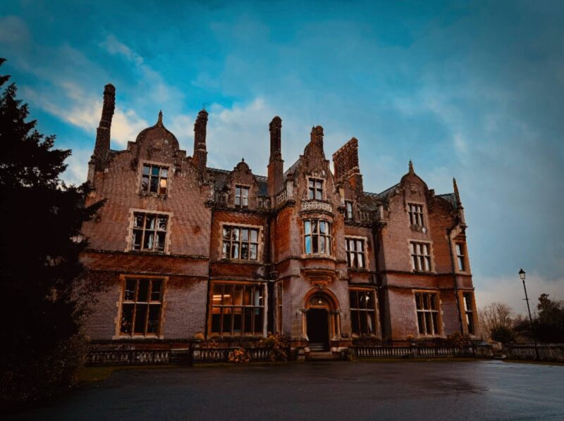 Façade historique du manoir Stansted Hall abritant l'Arthur Findlay College au crépuscule.